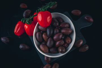 Food photography of a beautiful Greek olives with stunning red cherry tomatoes in a white plate