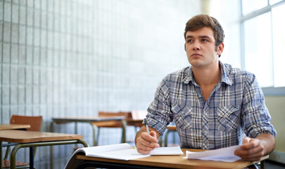 Dedicated to his education. Shot of a young college student studying in class.