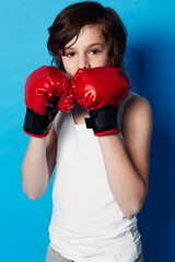 Training for the next big fight. Portrait of a young boy wearing boxing gloves in the studio.