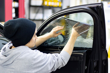 man at work installing window tint on a car