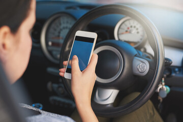 Distracted driving. Shot of a woman using a phone while driving.