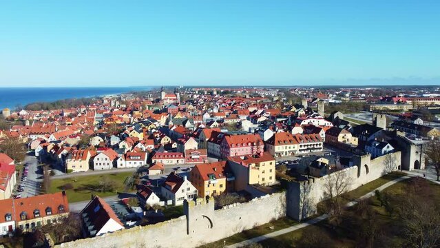 Aerial drone footage of the Visby medieval old town and its famous fortified wall in the Gotland island in Sweden on a sunny winter day. 