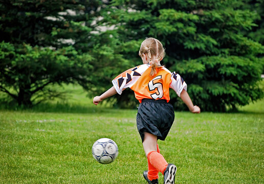 Little blond Caucasian girl playing soccer