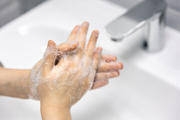 Close-up, the child washes his hands in the bathroom.