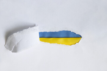 The yellow and blue national flag of Ukraine is seen from a torn piece of paper on a white background, stop the war and peace in Ukraine, stop the war 2022