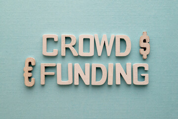 Crowd funding words written on wood blocks over blues background