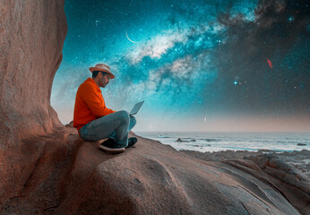 person silhouette with a laptop on the top of the mountain under the starry night 