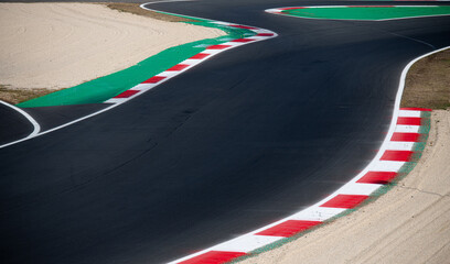Curving asphalt red and white kerb of empty race track, motor sports racing circuit high angle view