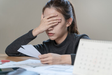 stressed young asian woman trying to find money to pay credit card debt.