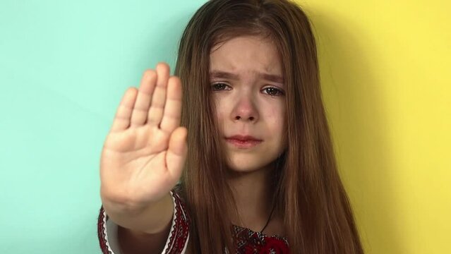 Ukrainian little girl shows STOP with her hand. Stop the war in Ukraine. Children against war.