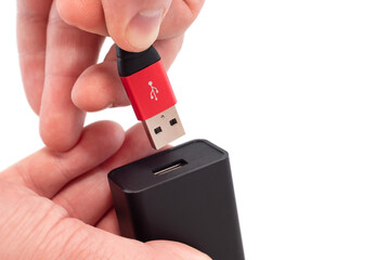 Hands connect the usb cable to the socket on a white background close-up. USB connection