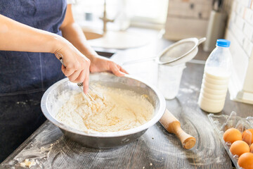 Baking concept. Woman in apron kneading dough for homemade pastries in kitchen interior