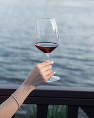 girls hold glasses of red wine in their hands on the seashore. holiday mood