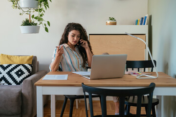 Businesswoman Talking on a Mobile Phone at Home Office
