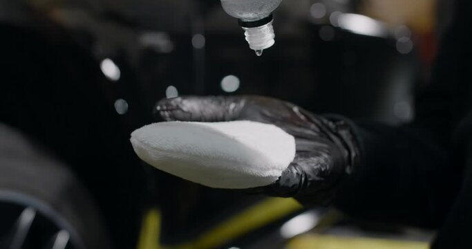 Detailer drops ceramic coating to the applicator before coating application to the car, 4k 60p