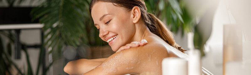 Portrait of smiling young woman bathing and taking care of her body at spa resort. Wellness, beauty concept