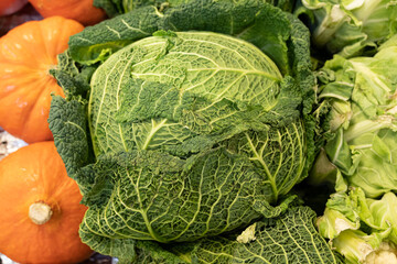 Fototapeta premium Gennevilliers, France - 01 21 2022: Primeur fruits and vegetables. Detail of green cabbage and pumpkins at a greengrocer
