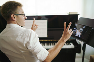 Scene of piano teacher cheer up his student while have lessons online training or E-class learning. Music learning from online network to teach students pupils learn from home. Social distancing.