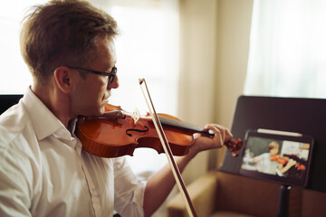 Scene of violin teacher teaching students by online music training or E-class learning while...