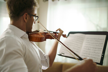 Scene of musician practicing violin in the music instrument room. © ztony1971