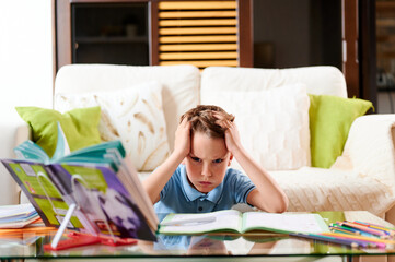 Tired and concentrated boy does homework at home. Homeschooling. Distance learning during quarantine