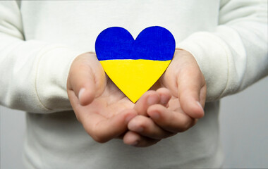 Girl holding a heart with the flag of Ukraine with both hands