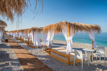 Canopy beach beds with white curtains on an empty beach in summer.