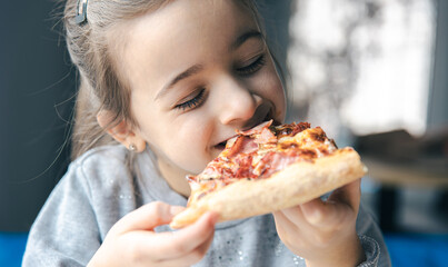 Portrait of a little girl with an appetizing piece of pizza.