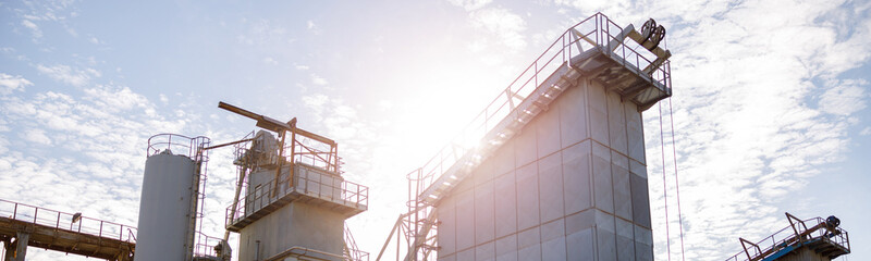 Manufacturing plant with industrial buildings, construction systems and ladders under cloudy sky