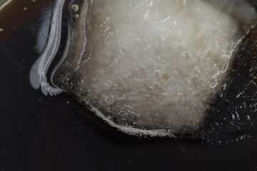 Melting ice cube in cola - macro photo.