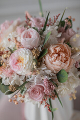 Bouquet with roses, hydrangea. Stabilized flowers in a white ceramic vase at home on the dressing table. Interior decor.