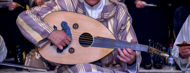 A Moroccan player wearing a djellaba plays the oud