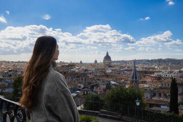 Naklejka premium Young tourist woman with long dark hair looks at the panorama view of Rome from above