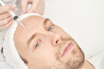 Injection at spa salon. Doctor hands in gloves. Closeup. Pretty male patient. Beauty treatment....