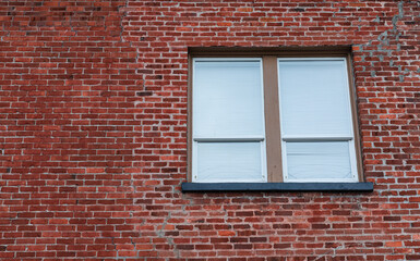 Window in Brick Wall. Window with closed blinds in a urban red bricks clinker house.