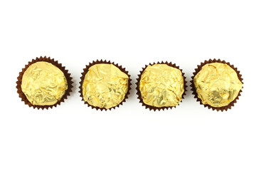 Four chocolate truffle balls wrapped in golden color foil isolated on white background