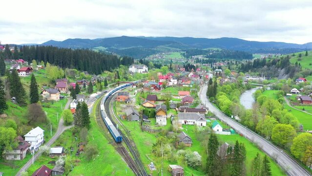 Diesel train yellow-blue runs along the railway in the resort town of Vorokhta in the Carpathians, Ukraine. Blue mountains and picturesque landscapes.