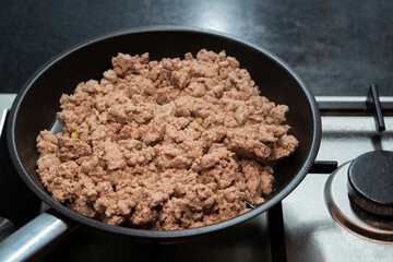 Frying minced meat with onions in a metal frying pan with non-stick coating on a stainless steel...