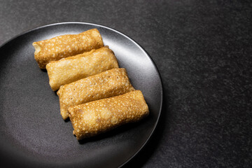 Fried pancakes stuffed with meat 4 pieces on a black plate on a dark background close-up top view copy space