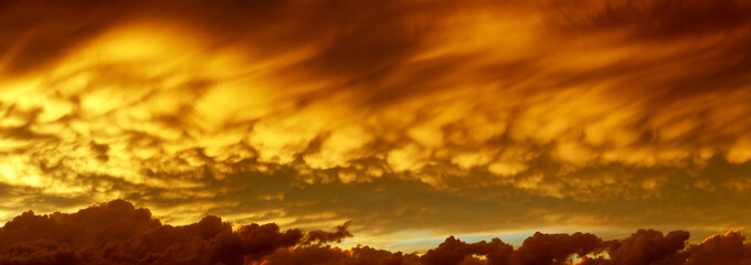 Sky on fire, panoramic view on sunset cloudscape in orange colors
