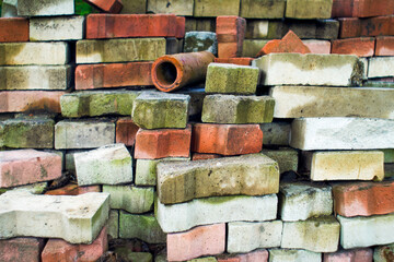 Pile of colored worn out and dirty 
paving bricks ready for recycling. Background created by used building cube. Waste tiles resulting from the replacement of the pavement.