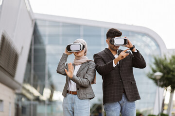 Front view of two multiethnic business people freelancer wearing modern glasses virtial reality during work against outside modern building