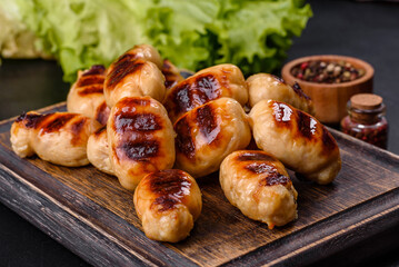 Grilled sausages with spices on a dark stone background