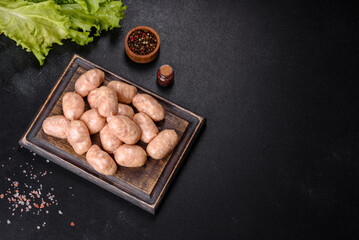 Raw sausages with ingredients on a cutting board on a stone background