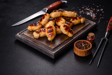 Grilled sausages with spices on a dark stone background