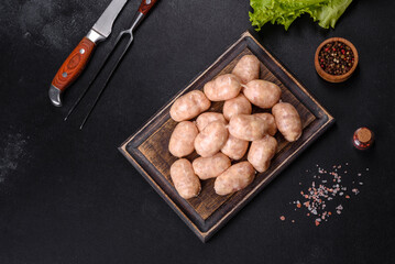 Raw sausages with ingredients on a cutting board on a stone background