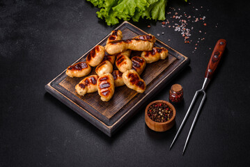 Grilled sausages with spices on a dark stone background