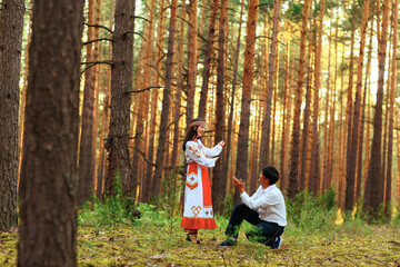 a girl in national Chuvash clothes and her boyfriend in a pine forest