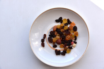 Plate with dried fruits on a white background