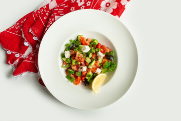 Turkish fresh Coban salad in a dish isolated on colorful table cloth top view on grey background...